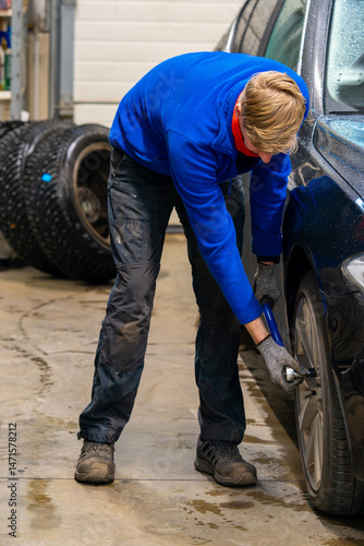 Obraz na plátně Skilled automotive technician changing winter tires in the professional service centre