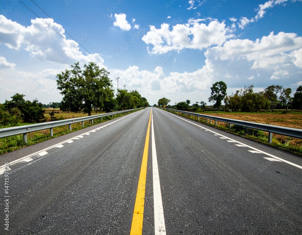 Fototapeta premium Expansive Open Road Under Bright Blue Sky and Fluffy White Clouds