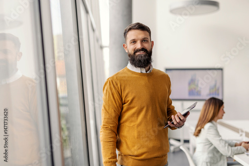 Fotografie Portrait of white collar worker standing at boardroom with tablet in hands during the meeting and smiling at camera