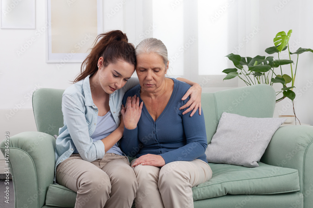Granddaughter hugs and comforts her elderly grandmother in a moment of sadness. Emotional family scene showing love, and support during a difficult time, disease pain, or family bereavement Granddaughter hugs and comforts her elderly grandmother in a moment of sadness. Emotional family scene showing love, and support during a difficult time, disease pain, or family bereavement