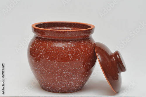 Brown ceramic pot with lid on white background.