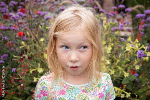 Smiling child girl blonde on a background of flowers