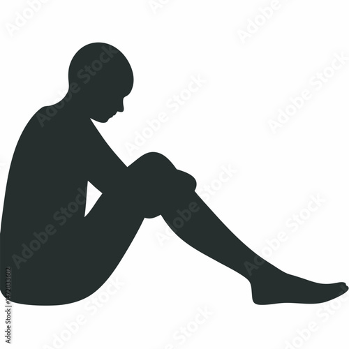 Silhouette of a young woman sitting with head down expressing sadness