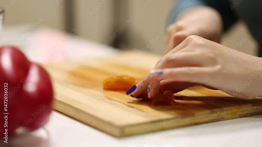 Close-up of woman's hands with blue nail polish carefully chopping walnuts with a knife on a wooden cutting board. Food preparation for a healthy meal or salad. Close-up of woman's hands with blue nail polish carefully chopping walnuts with a knife on a wooden cutting board. Food preparation for a healthy meal or salad.