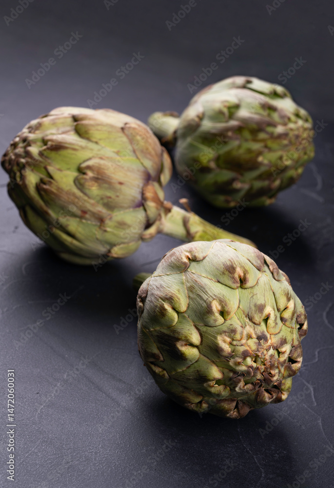 Obraz premium Scattered raw vegetables artichoke on dark bethic background