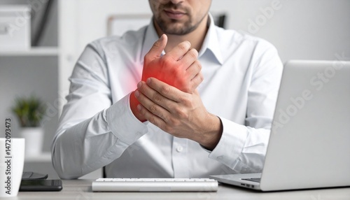 A man rubs his wrists after typing for a long time at his des