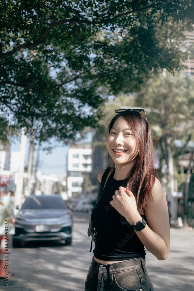 Fototapeta premium A woman wearing sunglasses and a black tank top is standing in front of a car