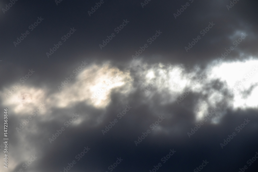 Fototapeta premium Dark storm clouds with sunlight behind