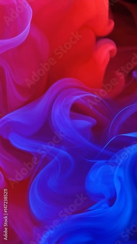 Vibrant red and blue ink clouds blend dramatically in liquid Motion captures swirling patterns as colors mix gradually transforming from separate hues to purple where they meet in hypnotic fluid dance