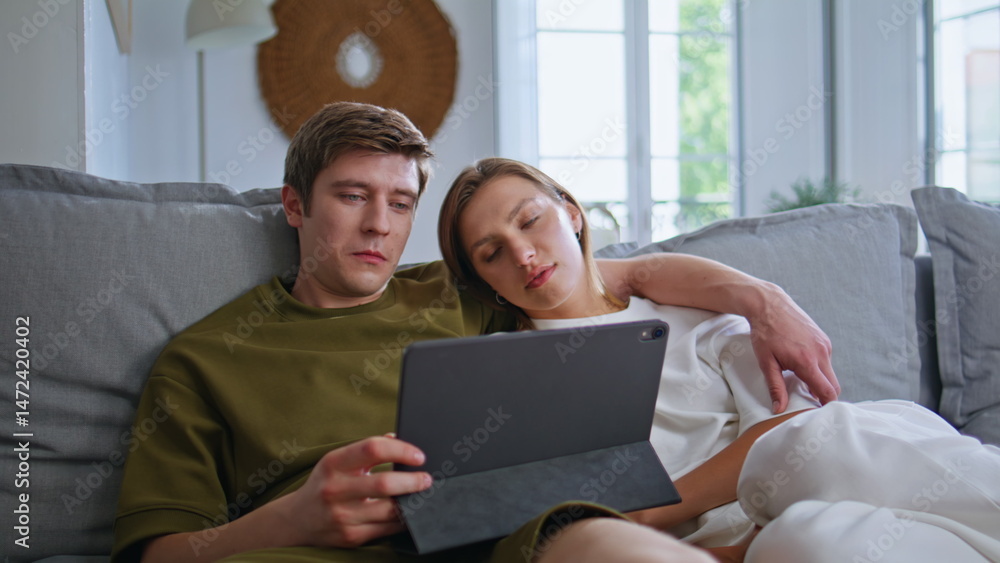 Relaxed teenagers looking pad computer at home. Girlfriend boyfriend embracing