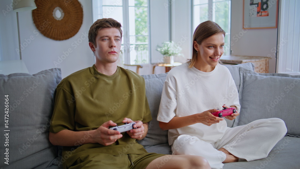 Smiling players enjoy video games sitting couch closeup. Couple playing online