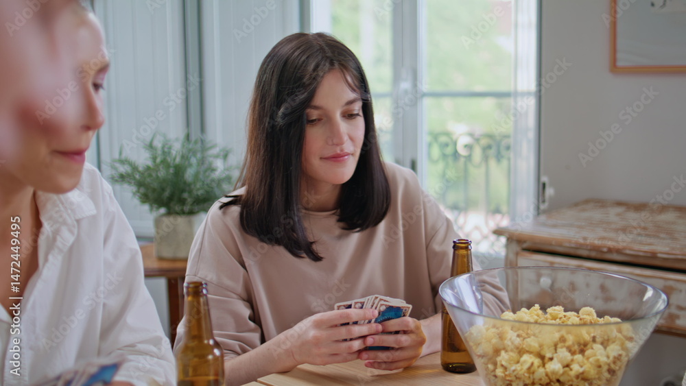 Company friends spend time together on table kitchen playing card game closeup