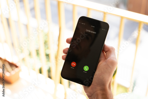 Fraud or fraudulent schemes. Close-up of a male hand holding a phone with an unexpected incoming call from an unknown