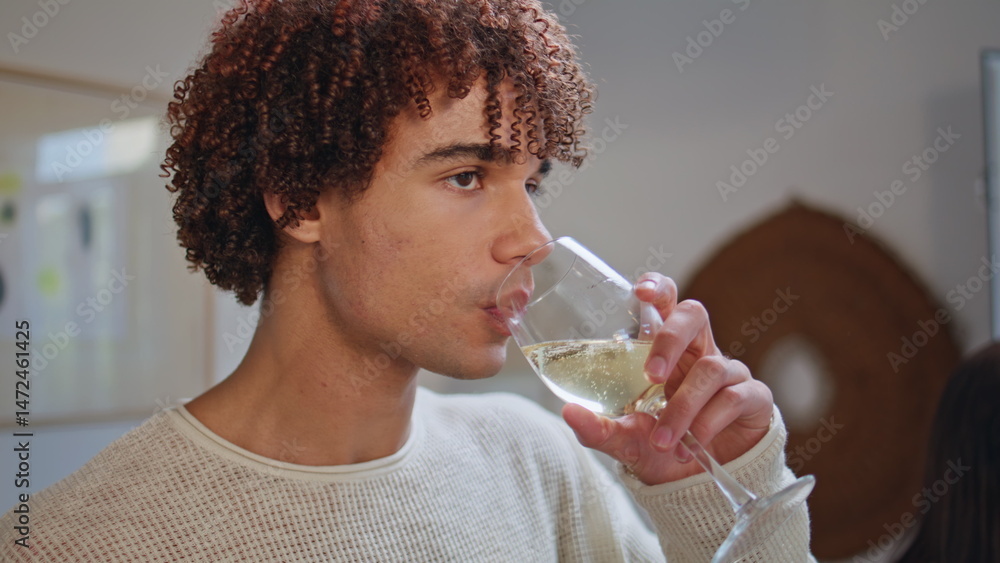Young guy sipping alcohol beverage resting home party closeup. Smiling student