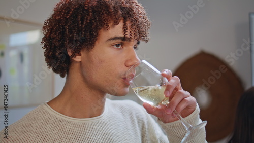 Obraz na płótnie Young guy sipping alcohol beverage resting home party closeup. Smiling student w salonie