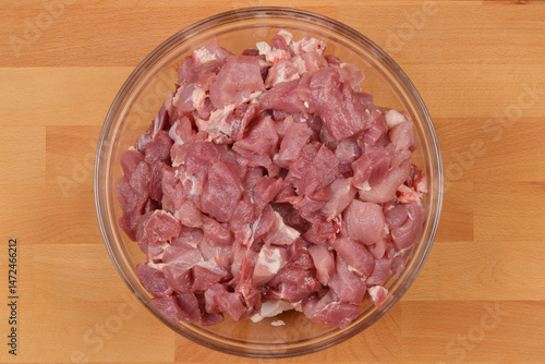 Obraz na płótnie A clear glass bowl filled with diced raw pork sits on a wooden cutting board w salonie