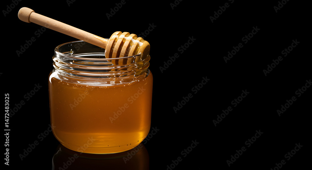 Close Up of Golden Honey in a Glass Jar with Wooden Dipper on Black Background Close Up of Golden Honey in a Glass Jar with Wooden Dipper on Black Background