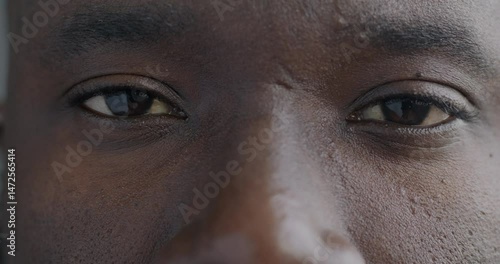 Close-up portrait of African American man's eyes looking at camera with no emotion. Human body part and face expression concept.