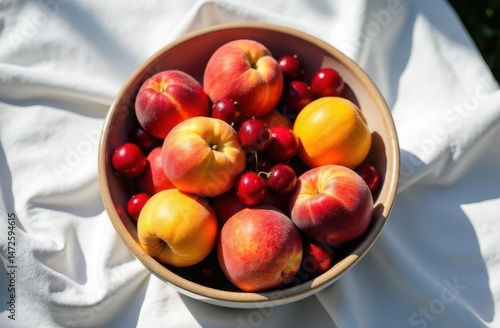 Top view of colorful fruit bowl with peaches, cherries and apricots on picnic