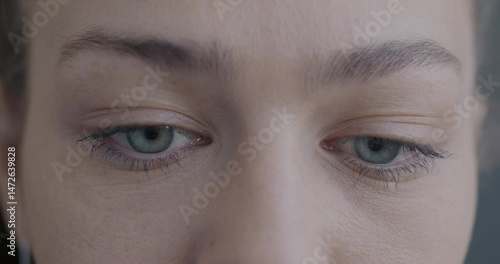 Close-up slow motion portrait of upset young woman's eyes looking at camera while lady feeling sad and confused. People and emotion concept.
