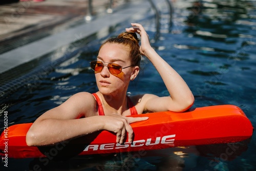 Lifeguard watching over bathers while holding rescue equipment
