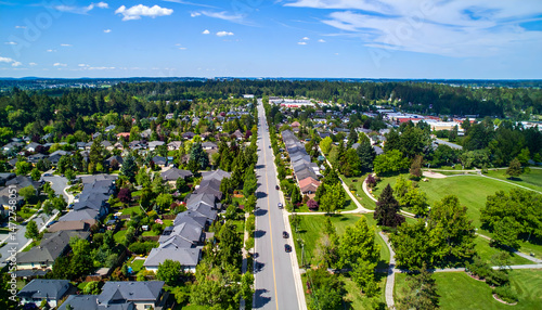 Aerial view of a suburban neighborhood showcasing tree-lined streets and residential homes under a clear sky (1)