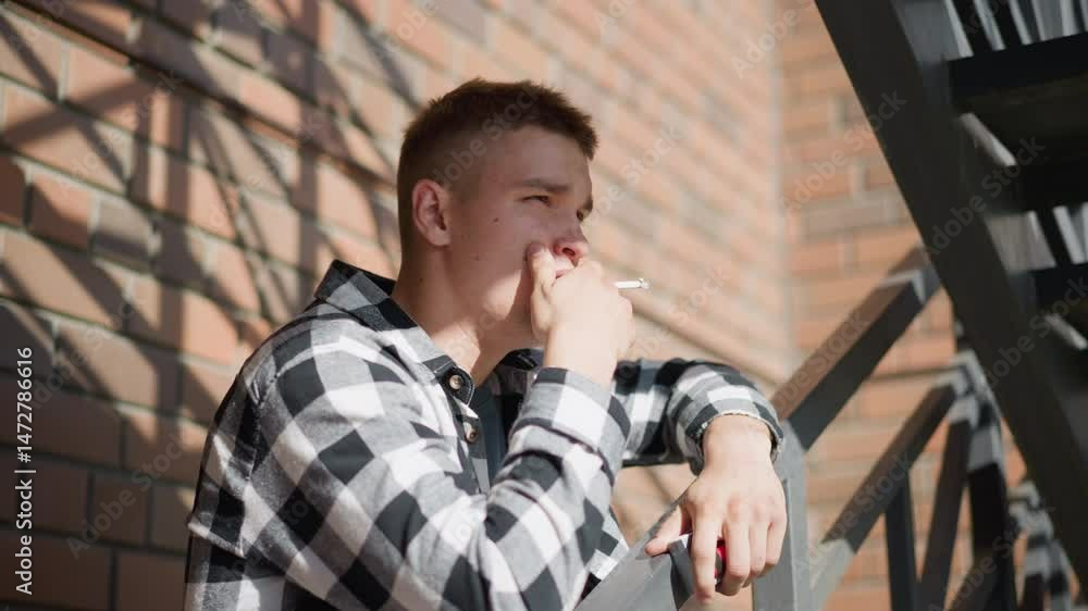 Smoking Railing side view of student resting on iron railing smoking cigarette while ...