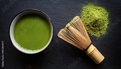 cup of fresh matcha tea bamboo whisk and green powder on black table top view