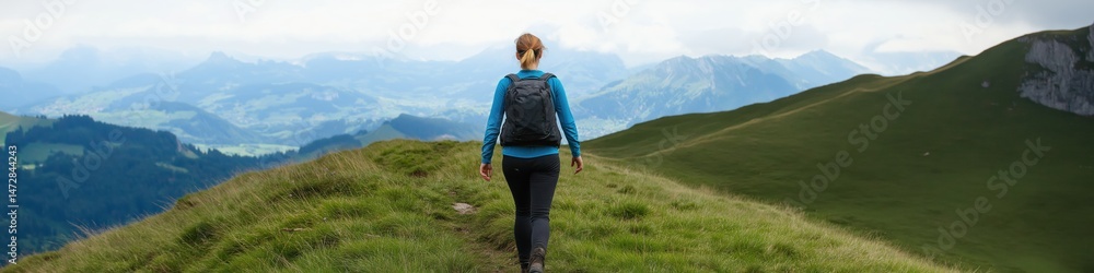 Fototapeta premium A woman is walking on a grassy hill with a backpack. The scene is peaceful and serene, with the mountains in the background adding to the sense of tranquility
