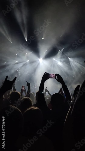 Clapping hands of people at a concert under spotlights.