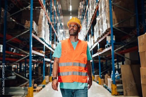 Warehouse worker walking through storage aisles and looking upwards