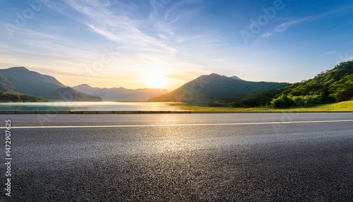 asphalt road and lake with green mountain scenery at sunset