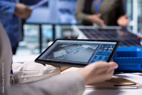 Photovoltaics factory manager visualizes factory floor designs with 3D software tools on tablet. Solar panels plant businessperson looking at computer simulations in CAD program on device