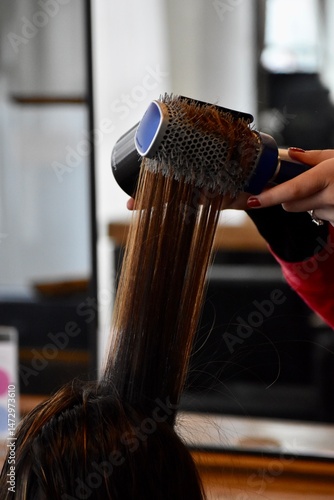 фотографія hairstylist blow drying hair
