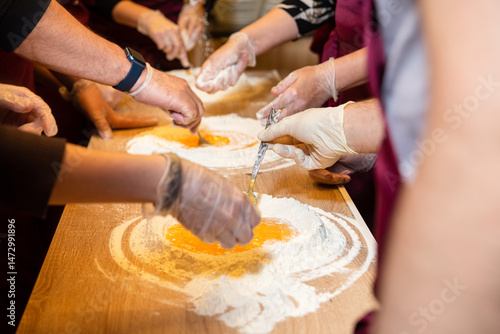 Hands mixing eggs and flour in cooking class.