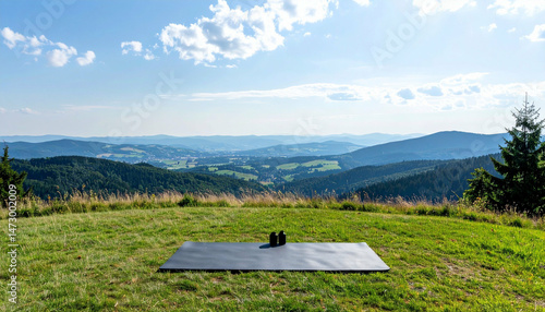 Outdoor workout setting with mat and weights on hilltop overlooking rolling hills & distant town