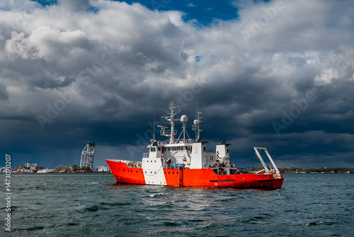 Red and White Coast Guard Ship on Open Sea Under Dramatic Stormy Sky, Port of Gdynia, Poland