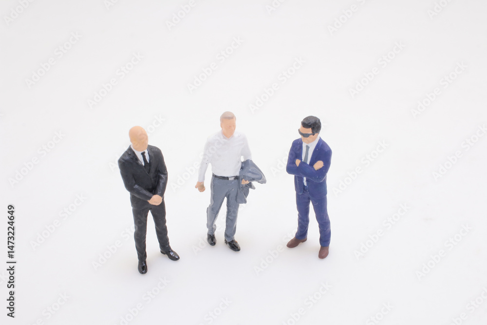 Miniature Business Figures Engaged in Casual Discussion on White Background Miniature Business Figures Engaged in Casual Discussion on White Background