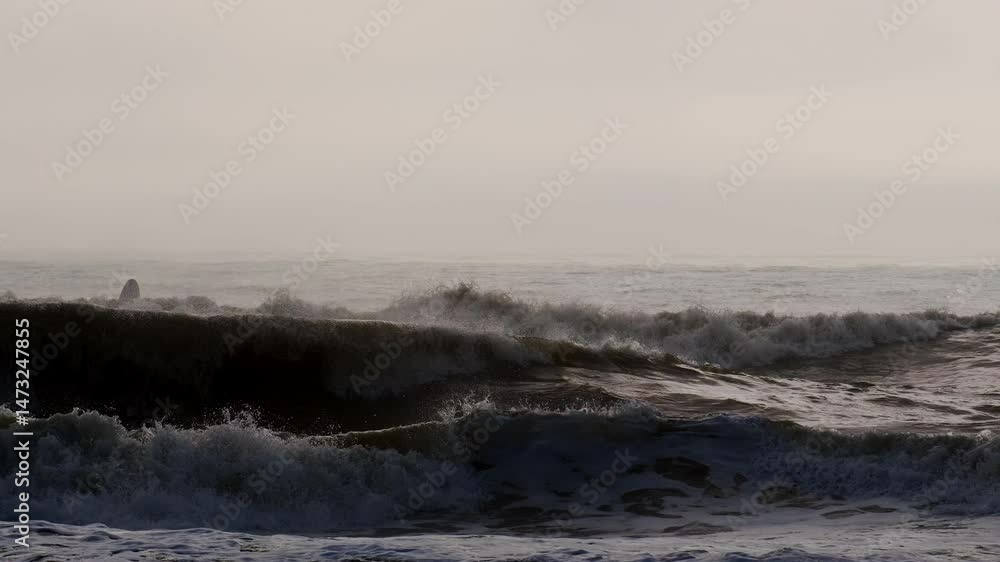Stormy ocean with rolling big foam waves on hazy sunny summer day Stormy ocean with rolling big foam waves on hazy sunny summer day