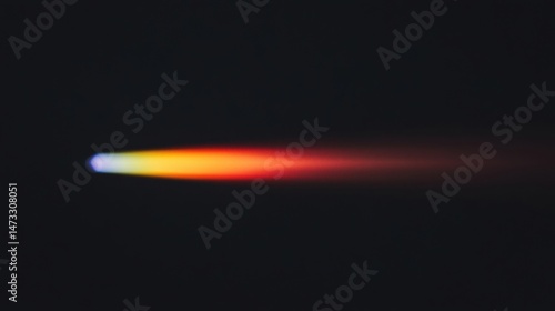 A bright, colorful streak of light moves across a dark background, resembling a fast-moving object or flame.