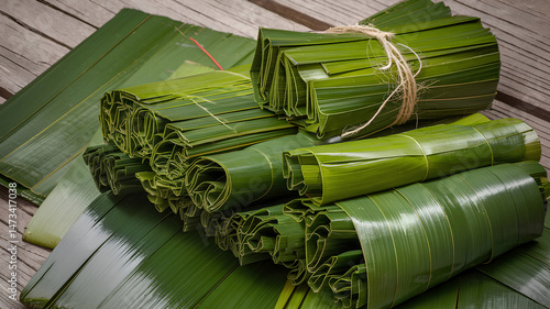 Bundles of Rolled Green Leaves Tied with String on Textured Wooden Surface