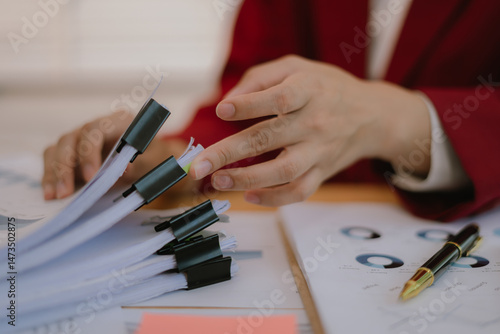 Asian businesswoman looking at finance, accounting, marketing and tax documents on desk in office.