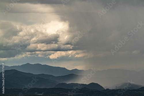 Bild auf Leinwand 重い雨雲から山の向こうに雨柱で土砂降りが降り注ぐ