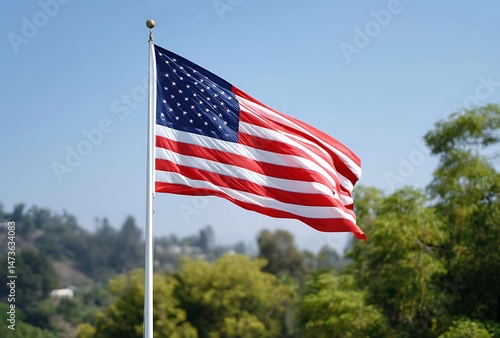American Flag Waving Proudly Against a Lush Green Landscape Under a Clear Blue Sky photo