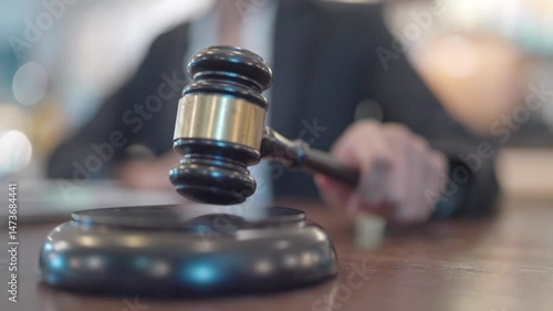 A person holding a gavel in front of a judge. The gavel is black and gold
