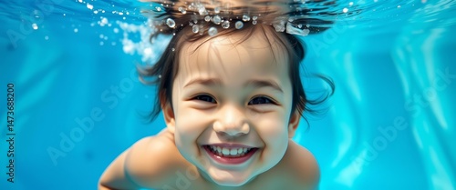 Smiling child underwater, blue pool background, portrait, joyful, stock photo