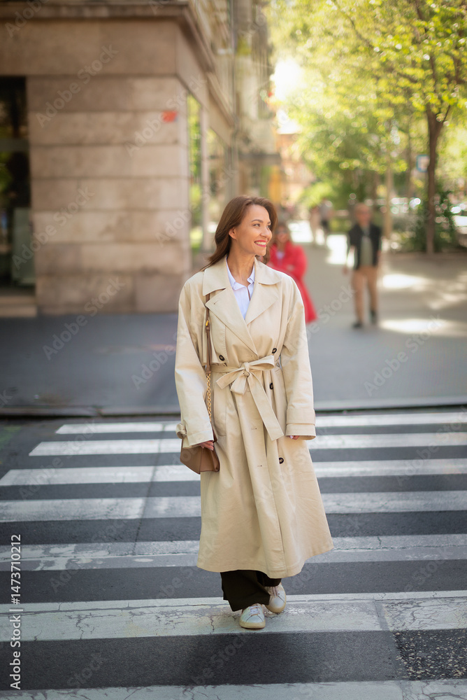 Fototapeta premium Full length of an attractive brunette haired woman walking through the pedestraian crossing in city