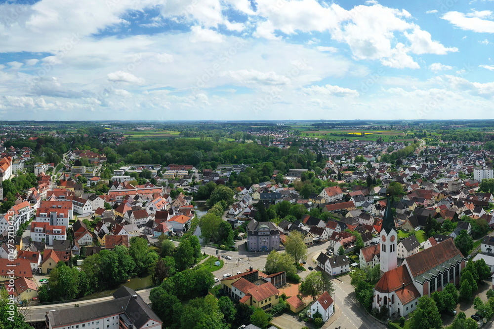 Obraz premium Eine beeindruckende Luftaufnahme von Günzburg, einer charmanten Stadt in Bayern. Die Stadt ist geprägt von einer harmonischen Mischung aus historischen und modernen Gebäuden mit roten Ziegeldächern.