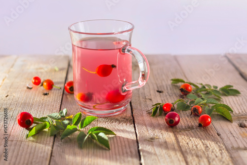 rose hips tea in glass cup on wooden background