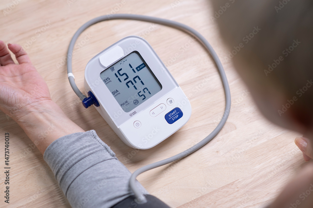Middle aged woman check blood pressure monitor and heart rate monitor with digital pressure gauge. Health care and Medical concept Middle aged woman check blood pressure monitor and heart rate monitor with digital pressure gauge. Health care and Medical concept